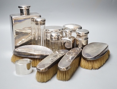 Six assorted George V silver mounted glass toilet jars, a similar brush set, a silver napkin ring and a large silver hip flask?, London, 1919, 17.3cm, 12.5oz.